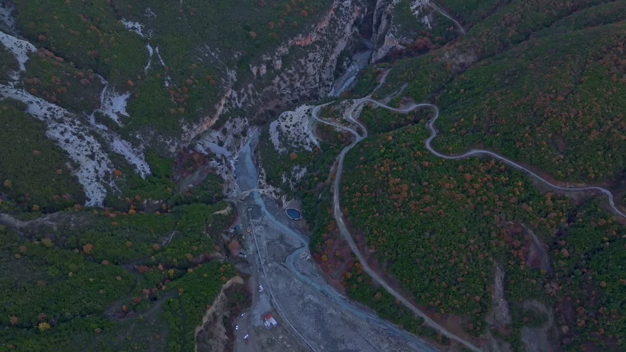Luftfoto af en skovklædt kløft med en snoet vej i efterårsfarver, Albanien