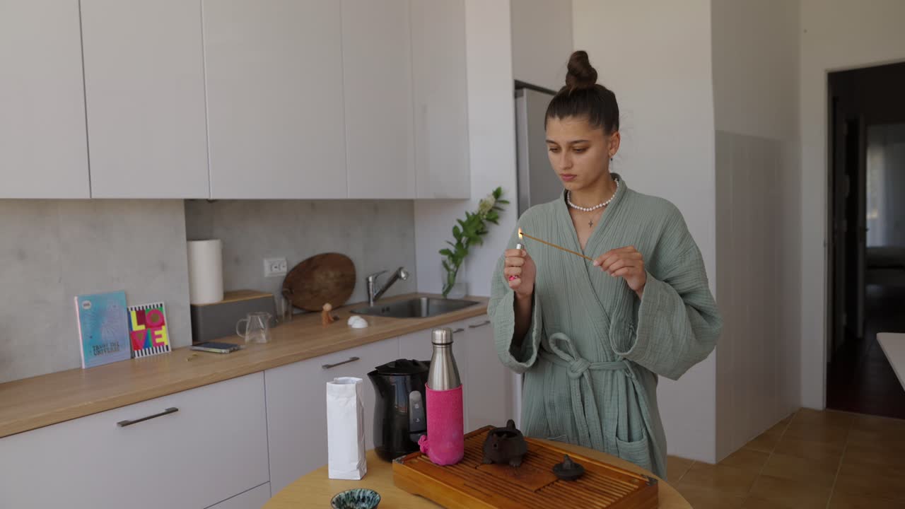 Woman lighting incense in kitchen