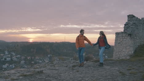 hombres y mujeres jóvenes encuentran ruinas de un antiguo castillo hermosa puesta de sol