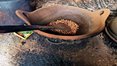close up view to a balinese traditional kitchen and culinary elements around green hindu canang flowers and luwak coffee grains being cooked