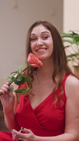 una dama posa colocando una rosa de cara para el arte. el modelo en vestido rojo inspira al pintor a encapsular el encanto seductor a través de trazos meticulosos de pincel