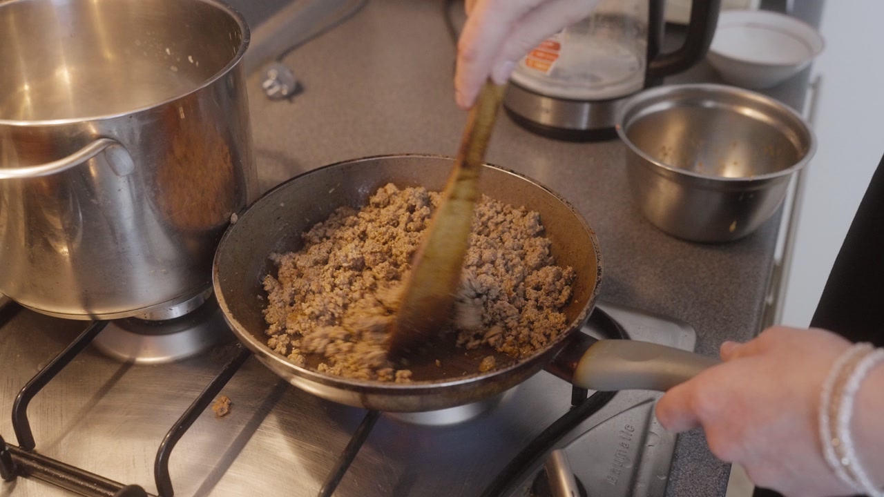 Cooking minced beef in pan, close-up kitchen scene.
Detailed food preparation with focus on texture and heat.