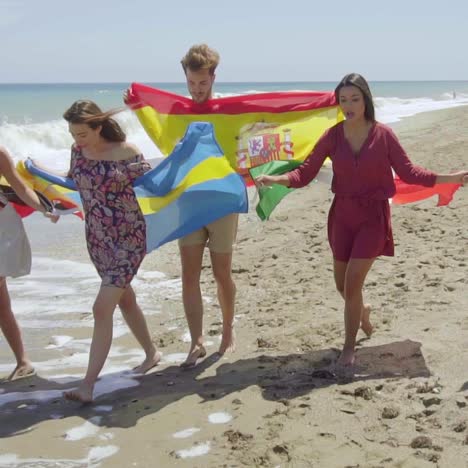 group of friends with flags walking on sunny beach