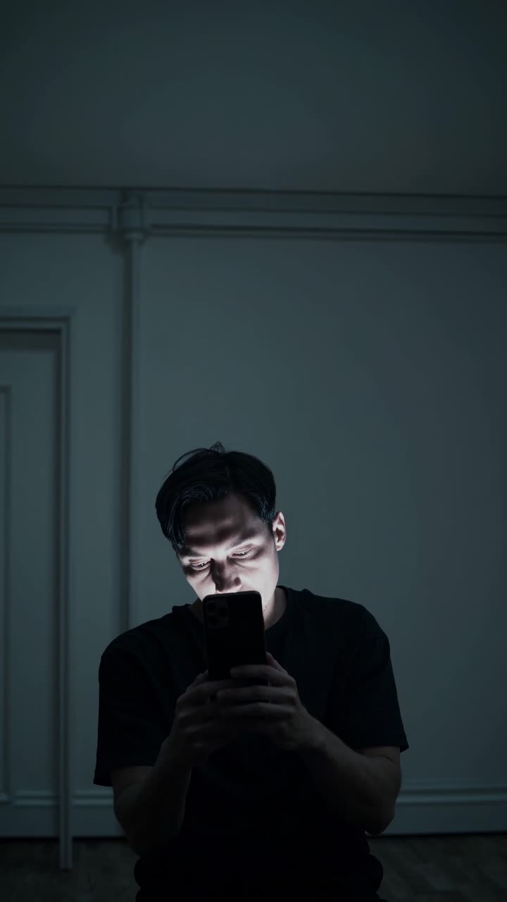 Individual engaged in focused activity, illuminated by device light, showcasing concentration and immersion in a dimly lit room environment