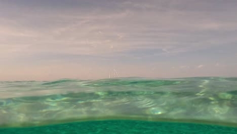 Medio-Bajo-El-Agua-De-Un-Velero-Amarrado-En-El-Horizonte,-Perspectiva-De-La-Superficie-Del-Agua-De-Mar