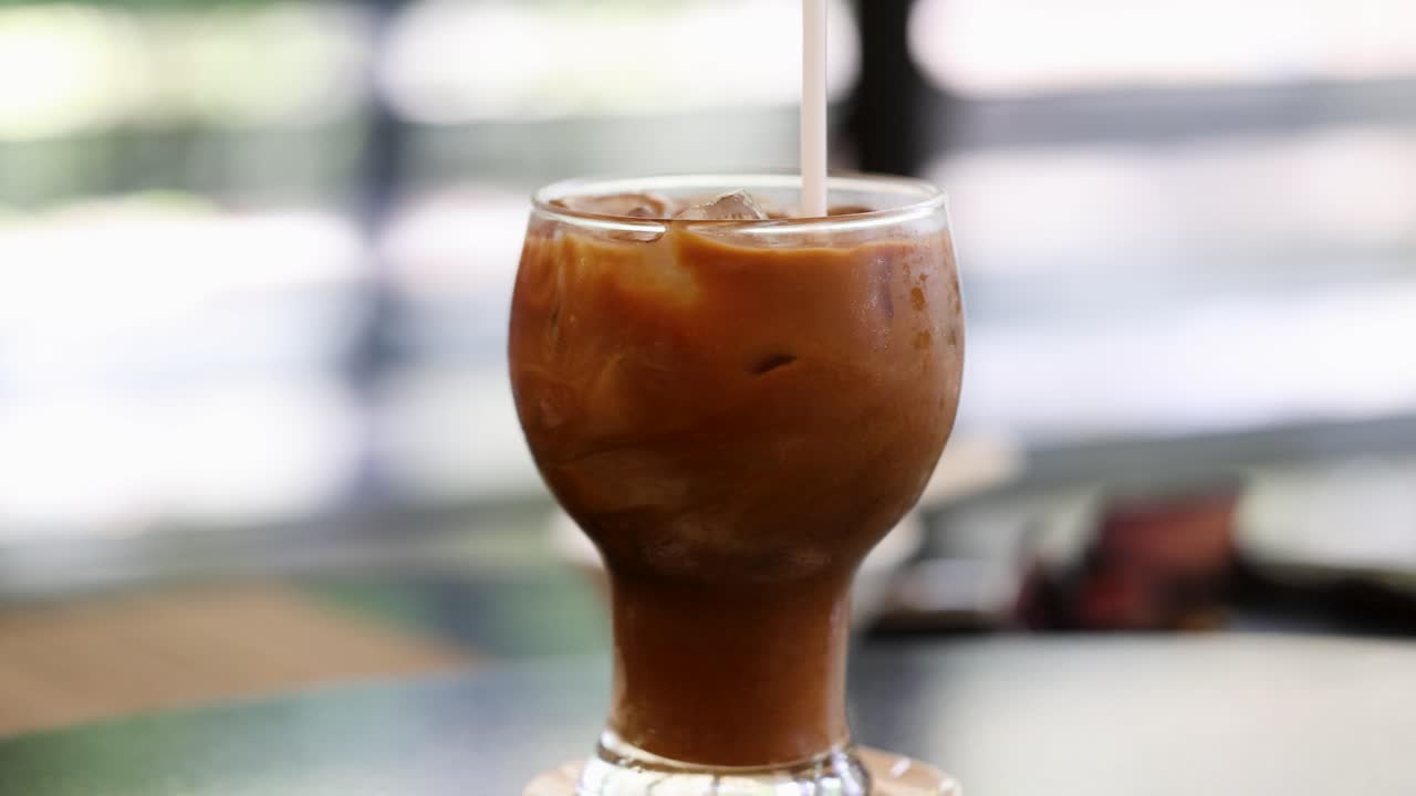 손은 으로 얼음 커피를 고, 밝고 편안한 환경에서 회전하는 패턴과 응축을 강조합니다.