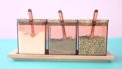 three spice containers on wooden tray