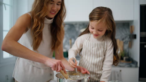 mother daughter hands creating dough home close up. positive family at kitchen