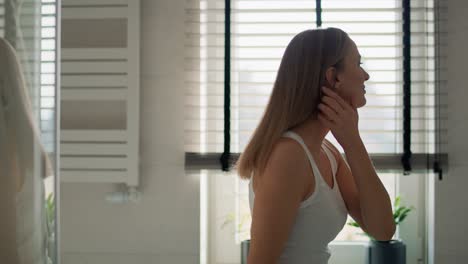 Side-view-of-young-caucasian-woman-standing-in-the-domestic-bathroom-and-stretching.