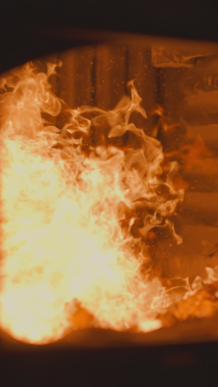 Burning charcoal in industrial furnace chamber with open door at metalworking factory. Flammable fossil fuel in direct fired heater used in boiler room