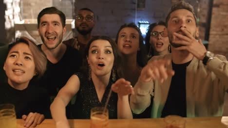 grupo de jóvenes extáticos multiétnicos viendo la competencia deportiva en el bar, gritando y celebrando el éxito de su equipo favorito