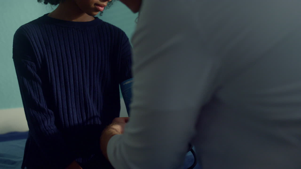 el pediatra mide la presión de una niña afroamericana usando un tonometro de cerca.