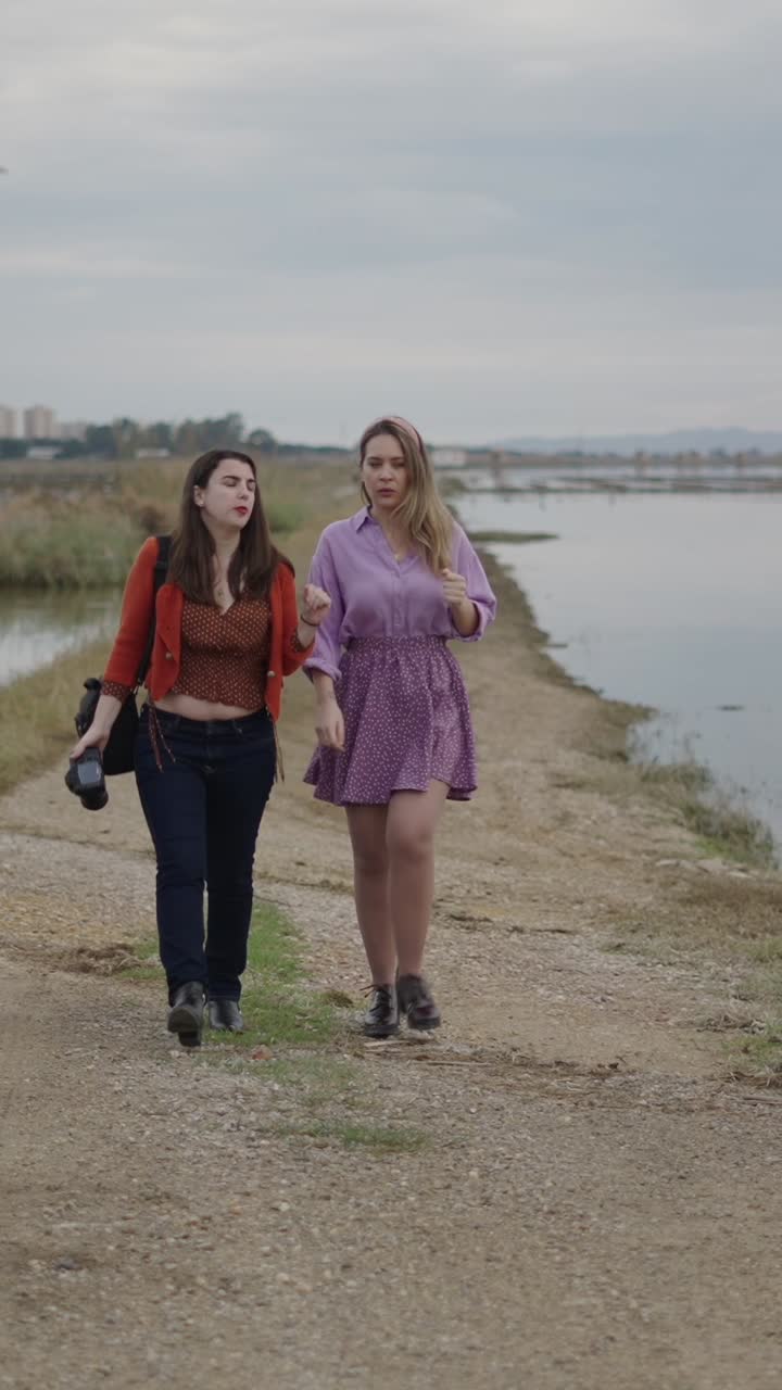 Two women walking near a field of water