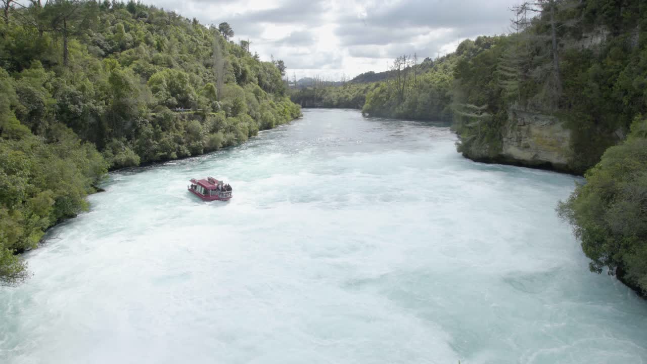 Un'inquadratura ampia dalla fine delle cascate Huka mentre una barca da crociera si avvicina.