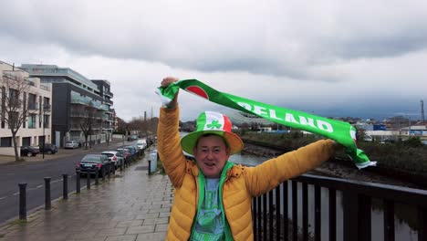 Celebrating-Ireland-near-the-East-End-of-Dublin-Ireland-near-the-Grand-Canal-waving-a-Green-scarf-with-Ireland-written-on-it