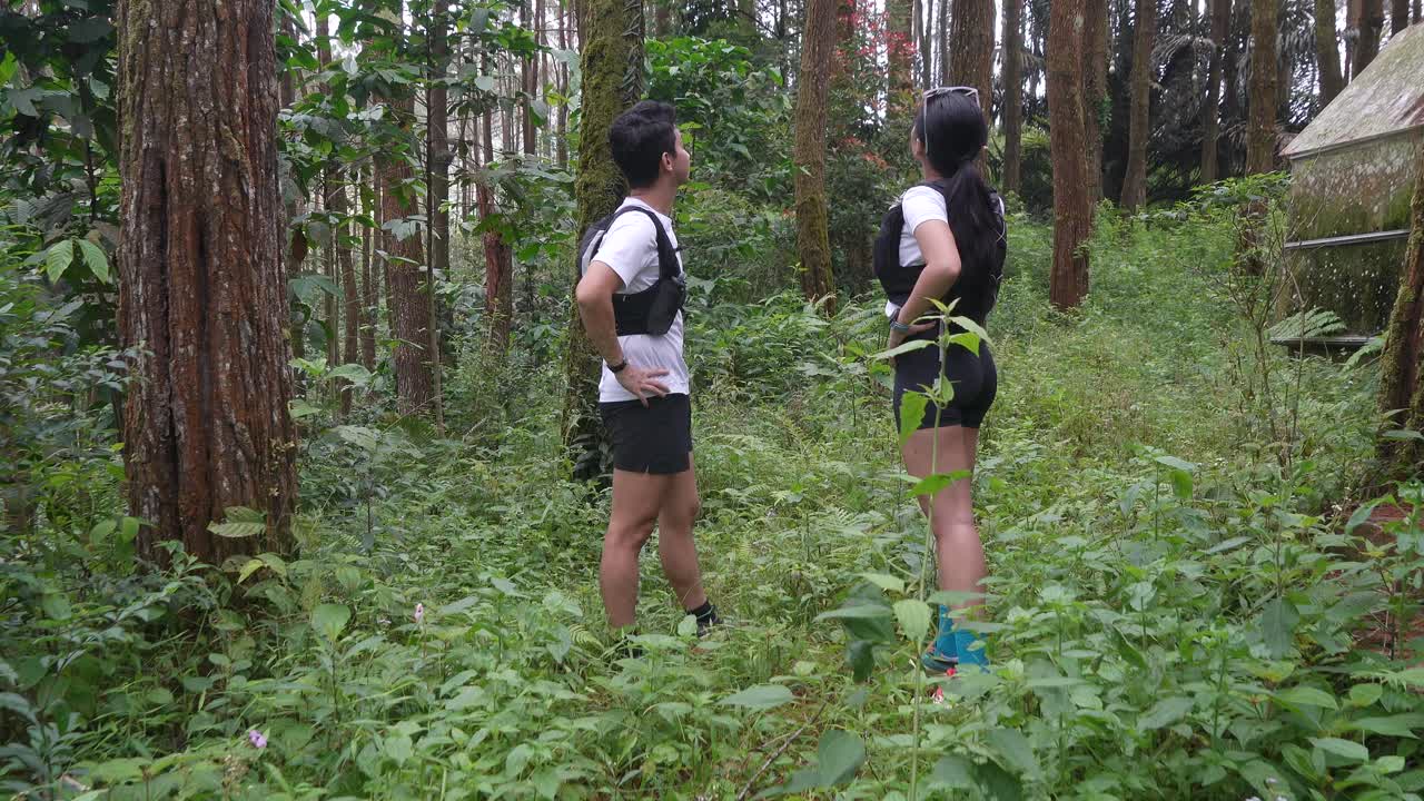 Asian couple resting and talking during outdoor workout in forest trail