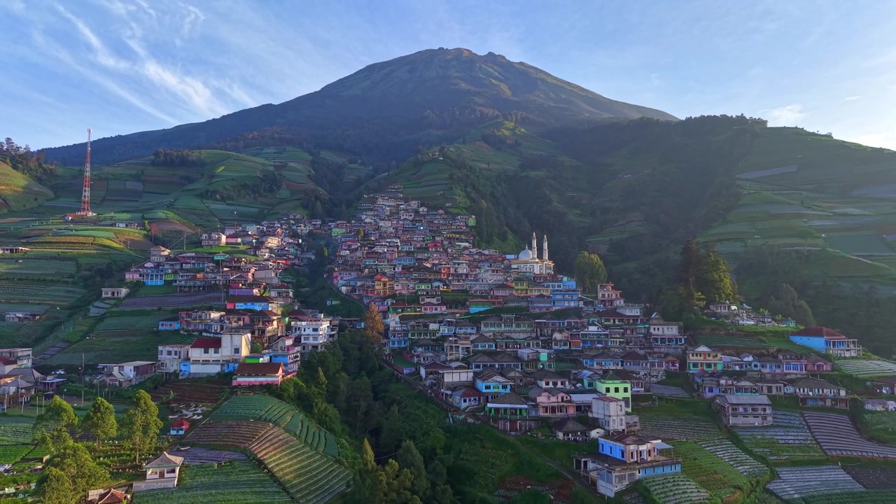 Splendido panorama aereo di un villaggio collinare sotto un'imponente cima montuosa. Ambiente rurale scenografico con fattorie, vegetazione e un'atmosfera di natura pacifica. Nepal Van Java, Indonesia