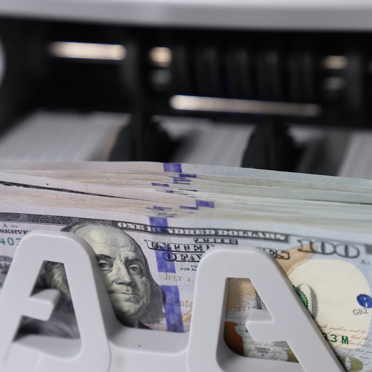 One hundred dollar wad being calculated in money counting machine. Benjamin Franklin portrait on the notes close up