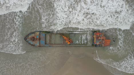 Abandoned-old-cargo-shipwreck-stuck-in-sandy-beach-in-Caribbean,-top-down