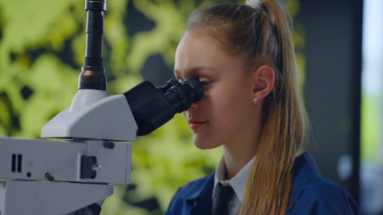 Girl Looking Through Microscope in a Science Lab