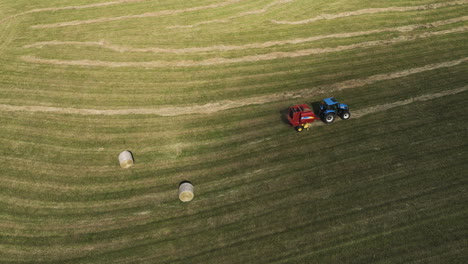 impresionante toma cinematográfica de las tierras de cultivo de otoño atendidas por un tractor y una prensa de paja