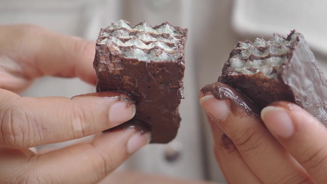Close-up of Hands Holding a Broken Chocolate Wafer Bar