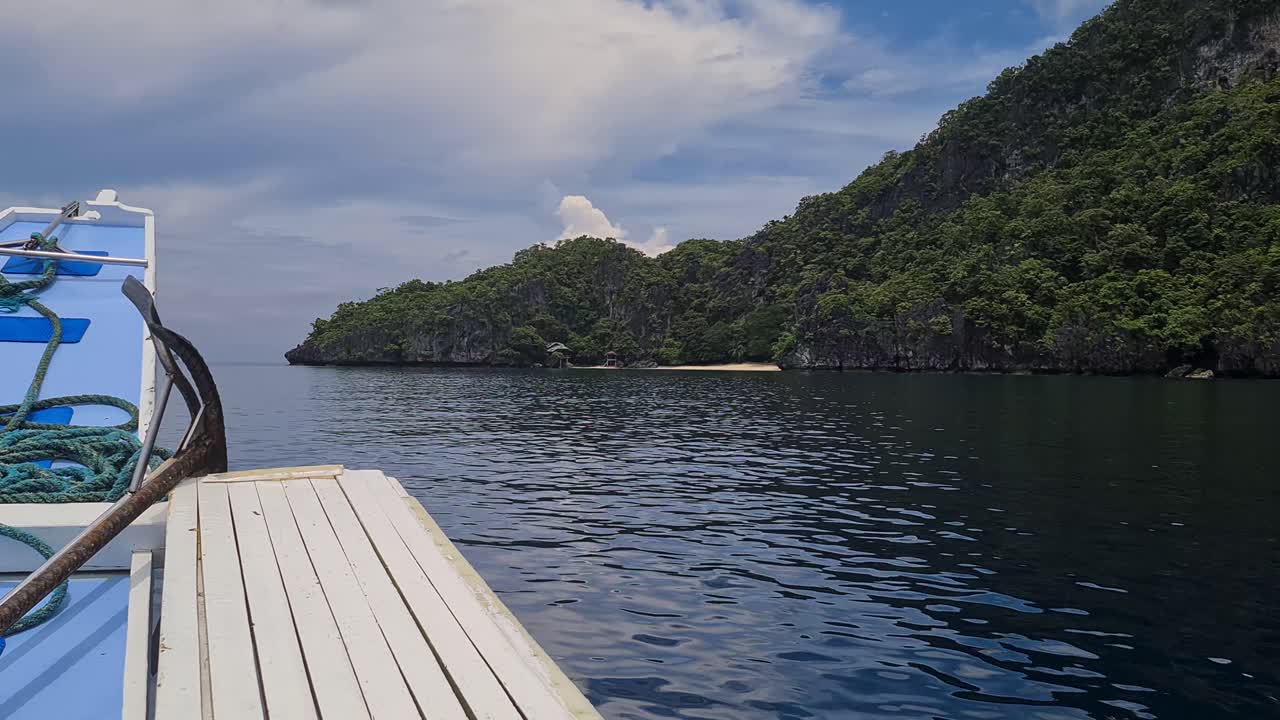 barco de madera navegando por una isla deshabitada y verde exuberante en colinas de piedra caliza y acantilados