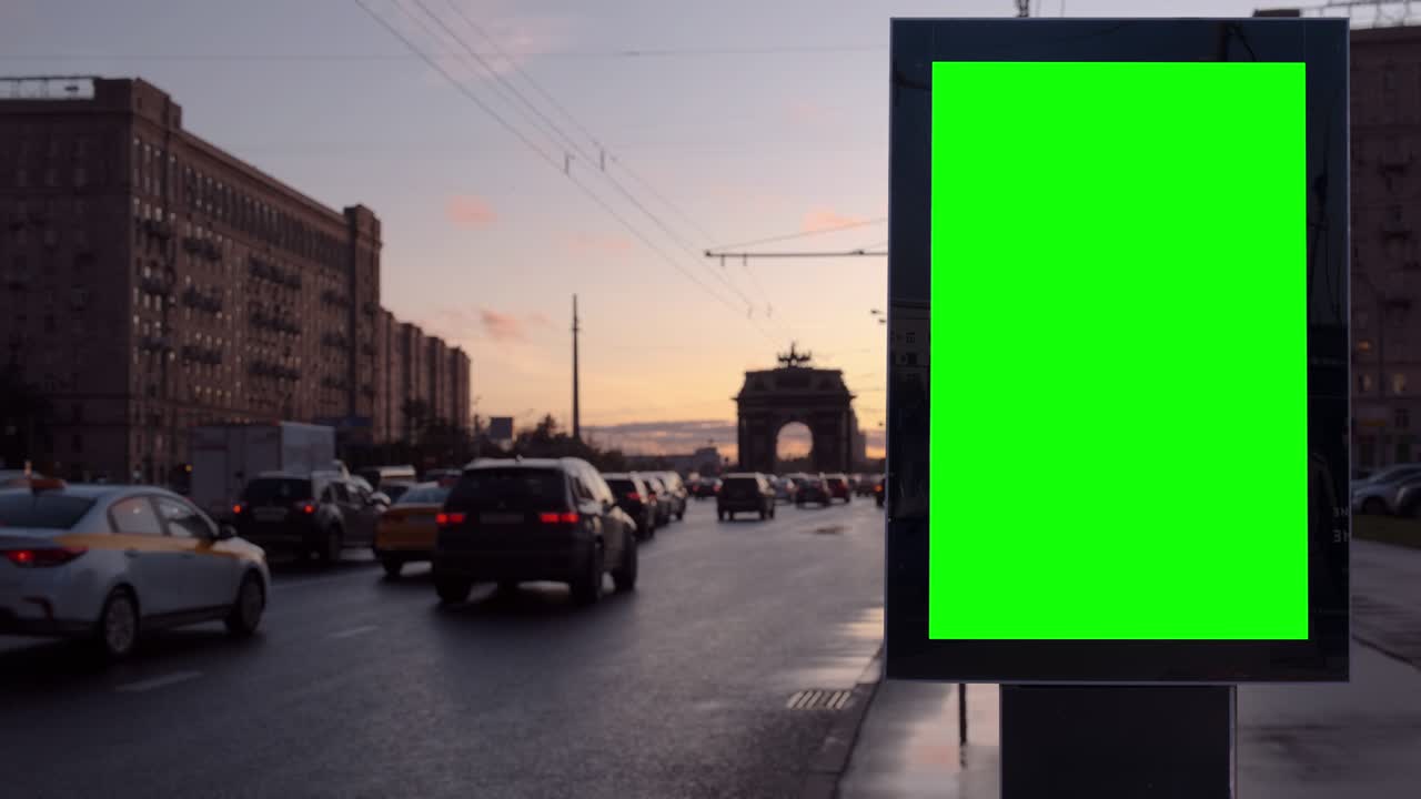 Cartellone pubblicitario vuoto con schermo verde su una strada trafficata al tramonto