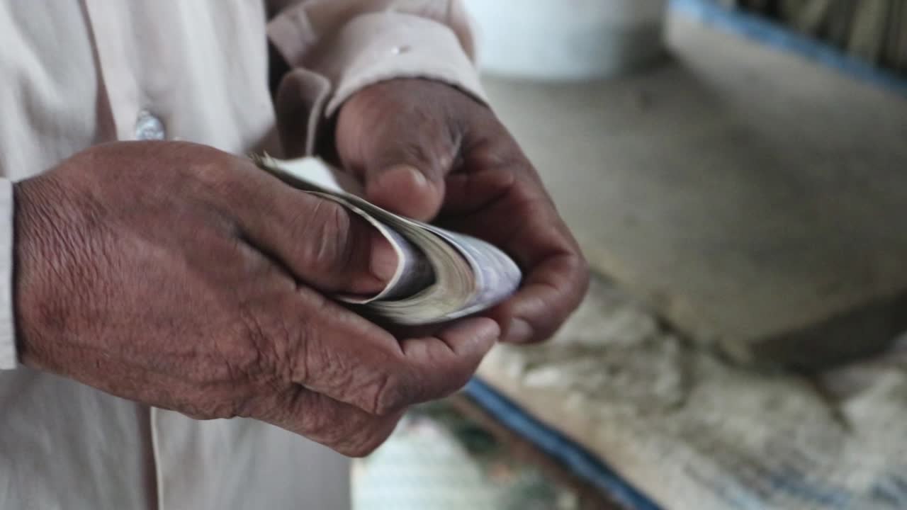 Close up video of the hands of a man holding local currency in the countryside in Cambodia