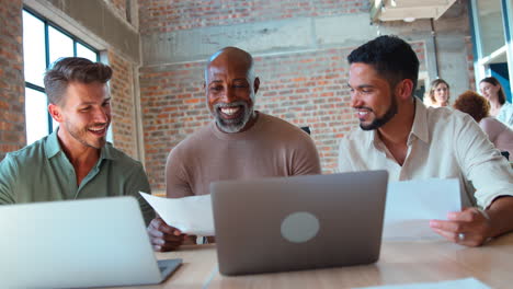 male multi-cultural business team meeting around laptop in office