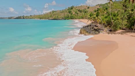 vista aérea de las olas que alcanzan la playa dorada con la costa tropical durante un día soleado - toma amplia estática