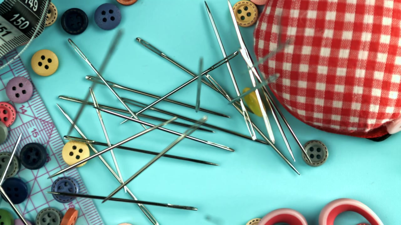 Sewing Needles Falling and Scattering on a Blue Background with Craft Supplies