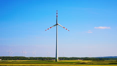 wind turbine stands tall in open field. a tall wind turbine generates renewable energy amidst vast green fields under a clear blue sky
