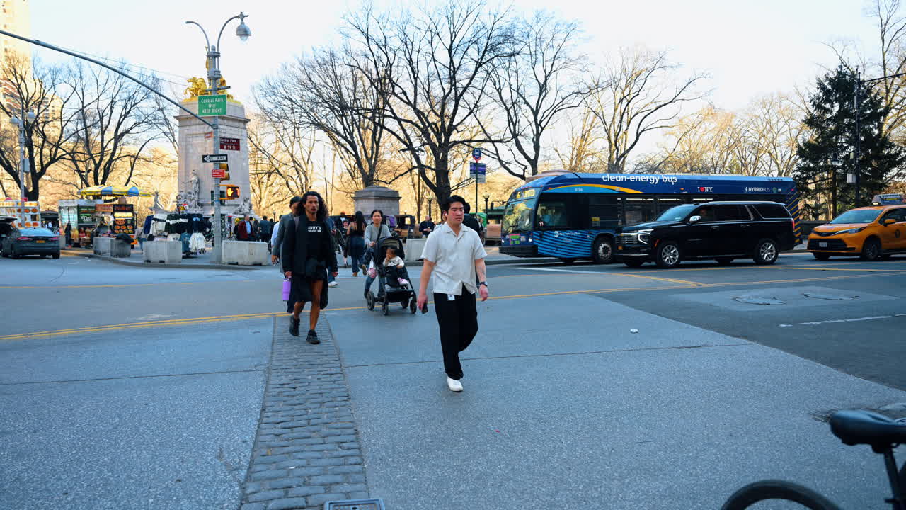 New York, USA, 26 March 2026: Entrance to Central Park at Columbus Circle with cyclists. People riding bicycles at busy intersection near Maine Monument in New York City