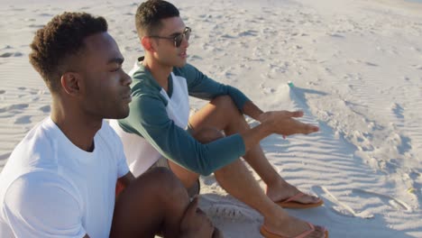 two young adult male friends relaxing on the beach 4k