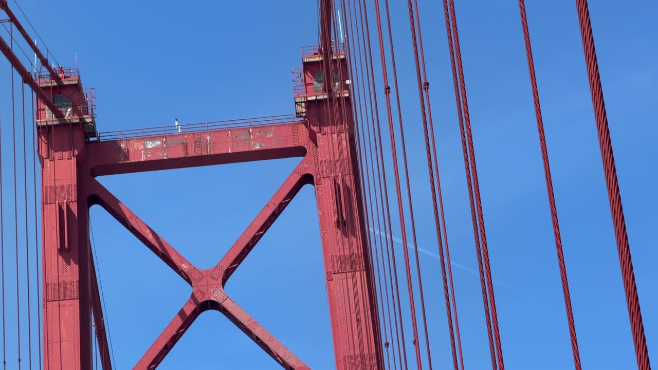 Upward View of Red Suspension Bridge Cables and Tower Against Blue Sky