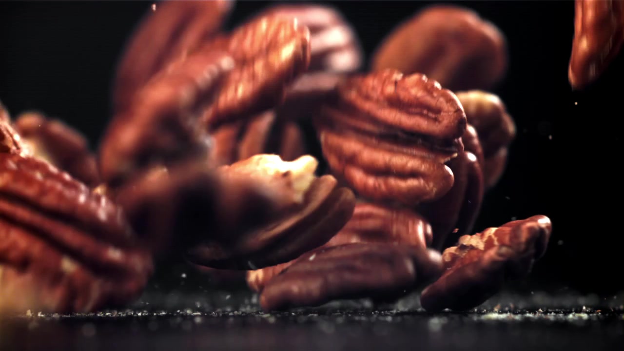 Noci pecan che cadono al rallentatore su sfondo scuro