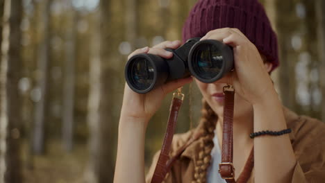 woman looking through binoculars in forest