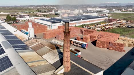 Aerial-shot-of-factory-chimney-and-solar-panels-on-the-rooftop-of-brick-factory