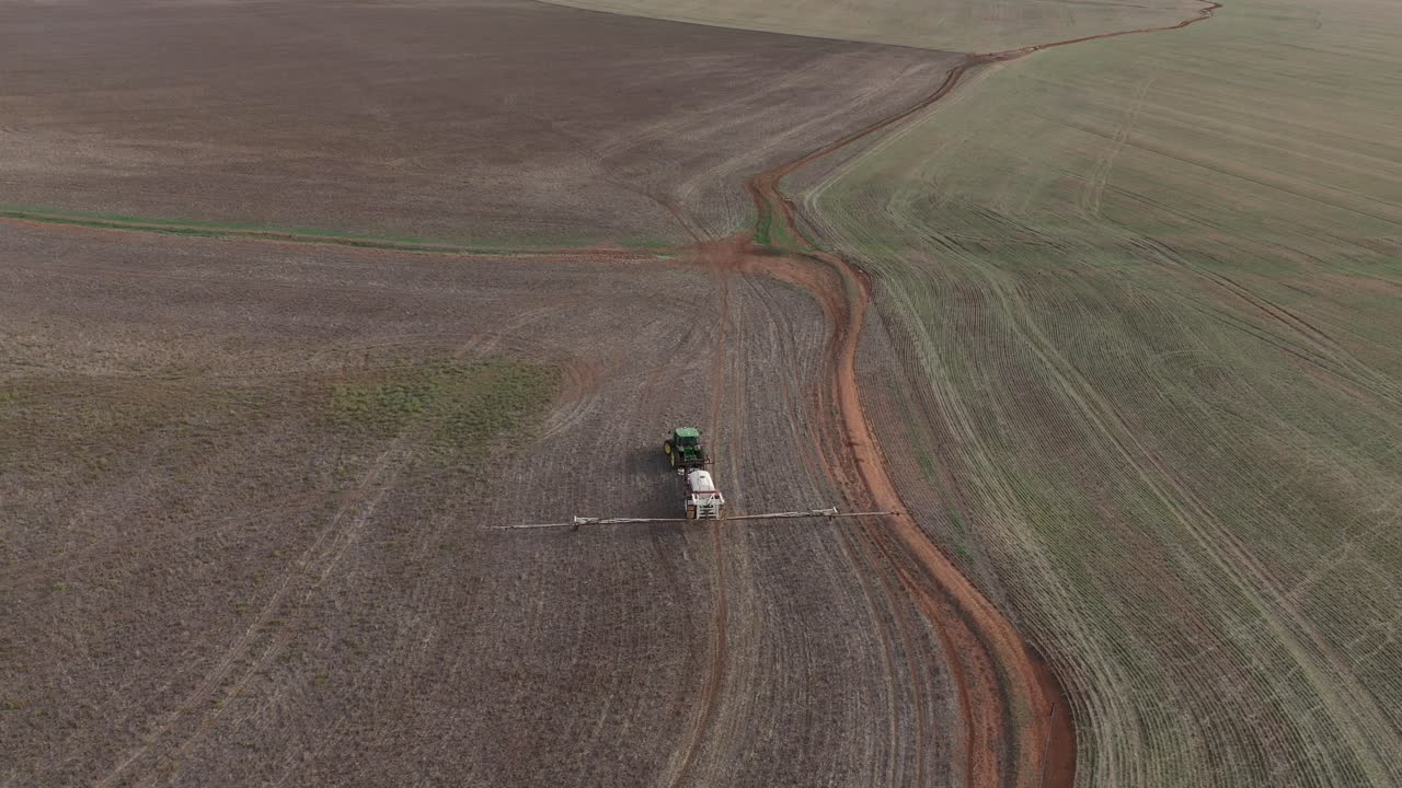 disparo de drones panorámico hacia abajo mirando el tractor agrícola conduciendo a través de un campo montañoso