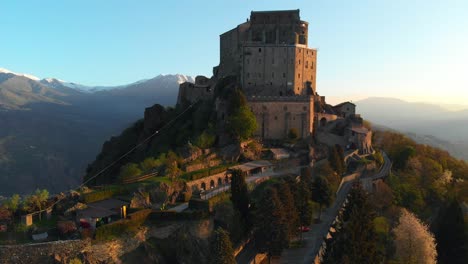 aerial: flight over old medieval abbey perched on mountain top - turin, italy