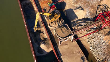 overhead aerial shot of excavator unloading sand from barge on the cumberland river in clarksville tennessee