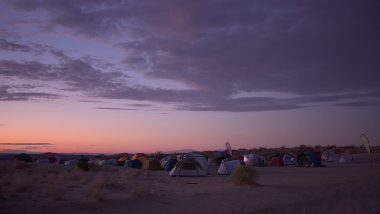보라색 하늘에 큰 구름과 함께 사막 메사에 캠핑하는 일몰 텐트