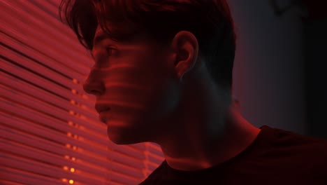 young man looking out a window at night