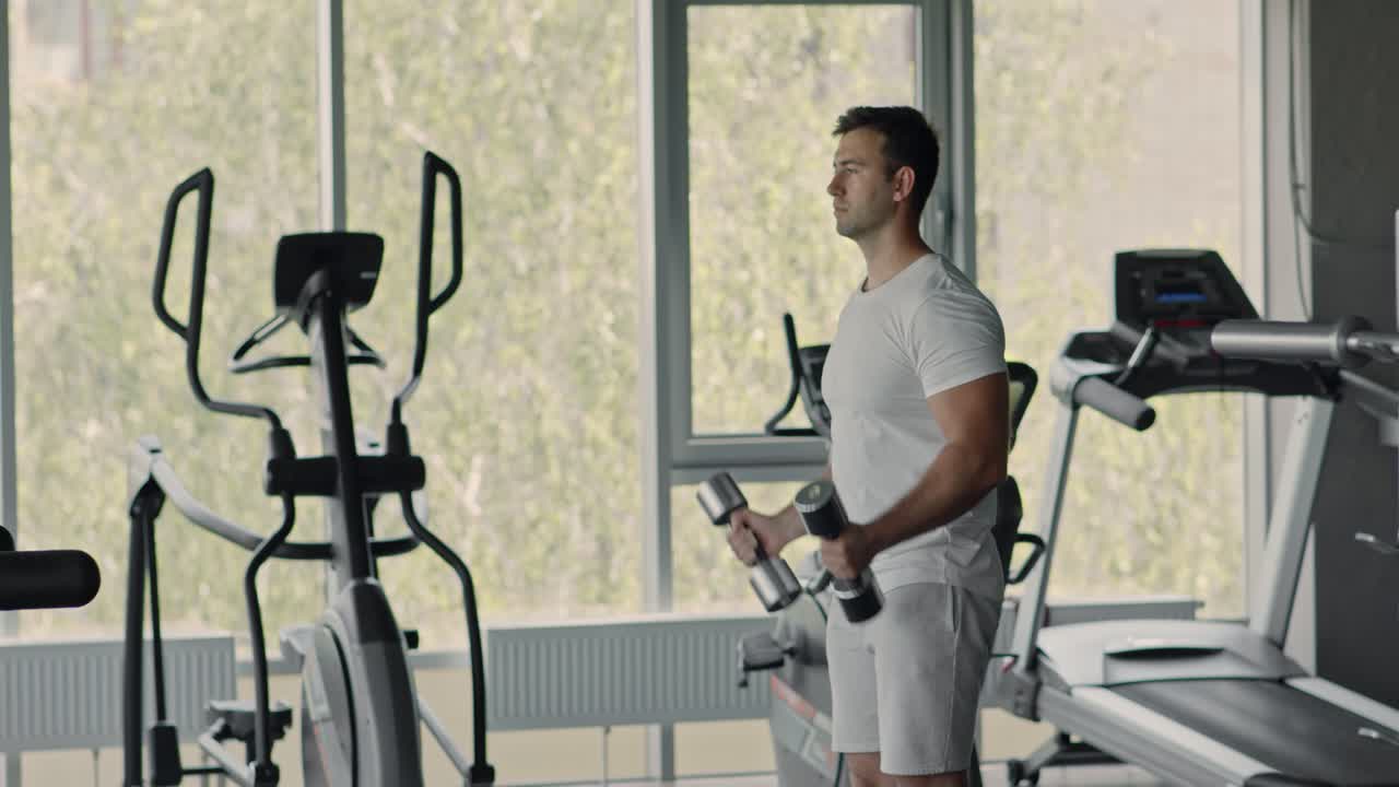 Uomo che si allena con i manubri in una palestra