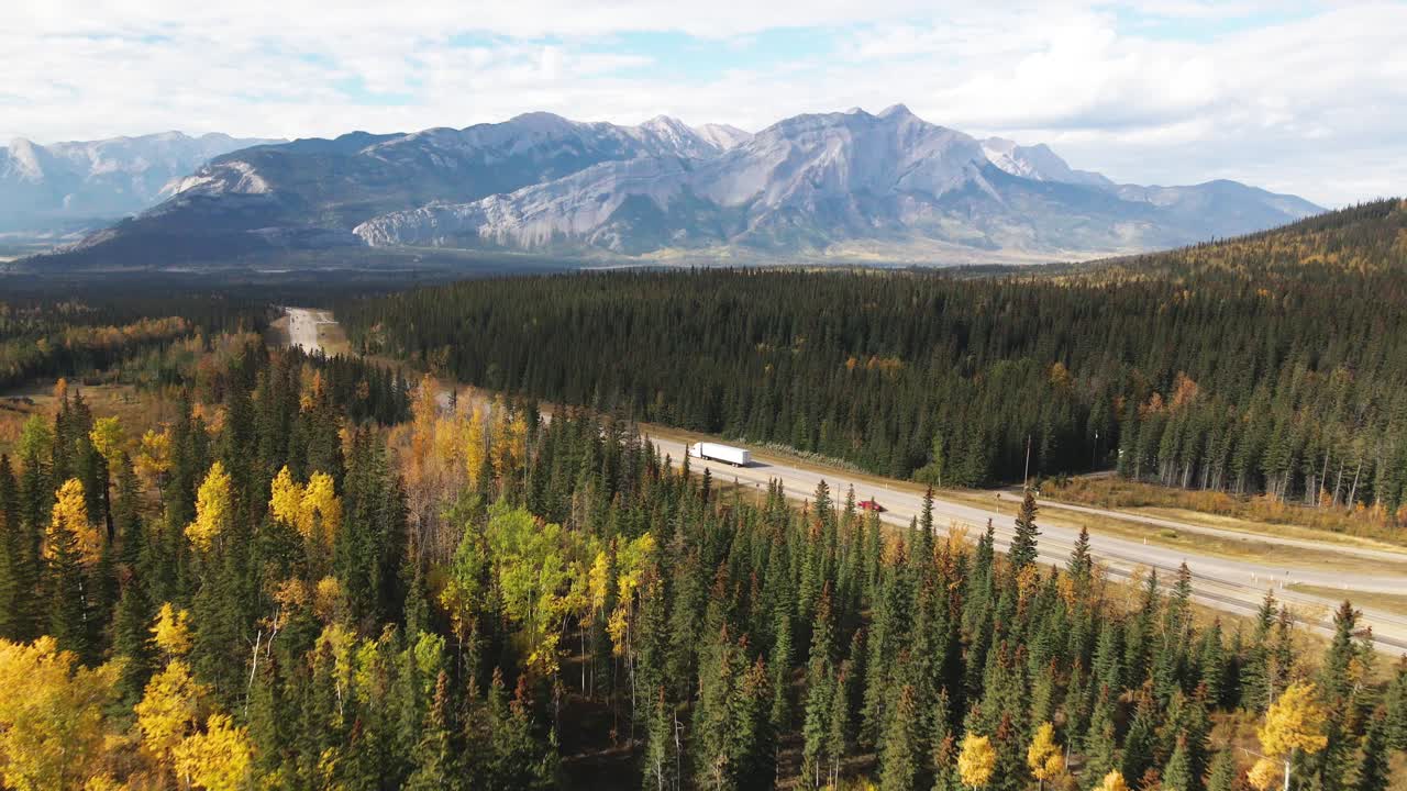 camión blanco conduciendo por la autopista 5 de cabeza amarilla con el parque nacional jasper al fondo en otoño con árboles de colores vivos en un día nublado