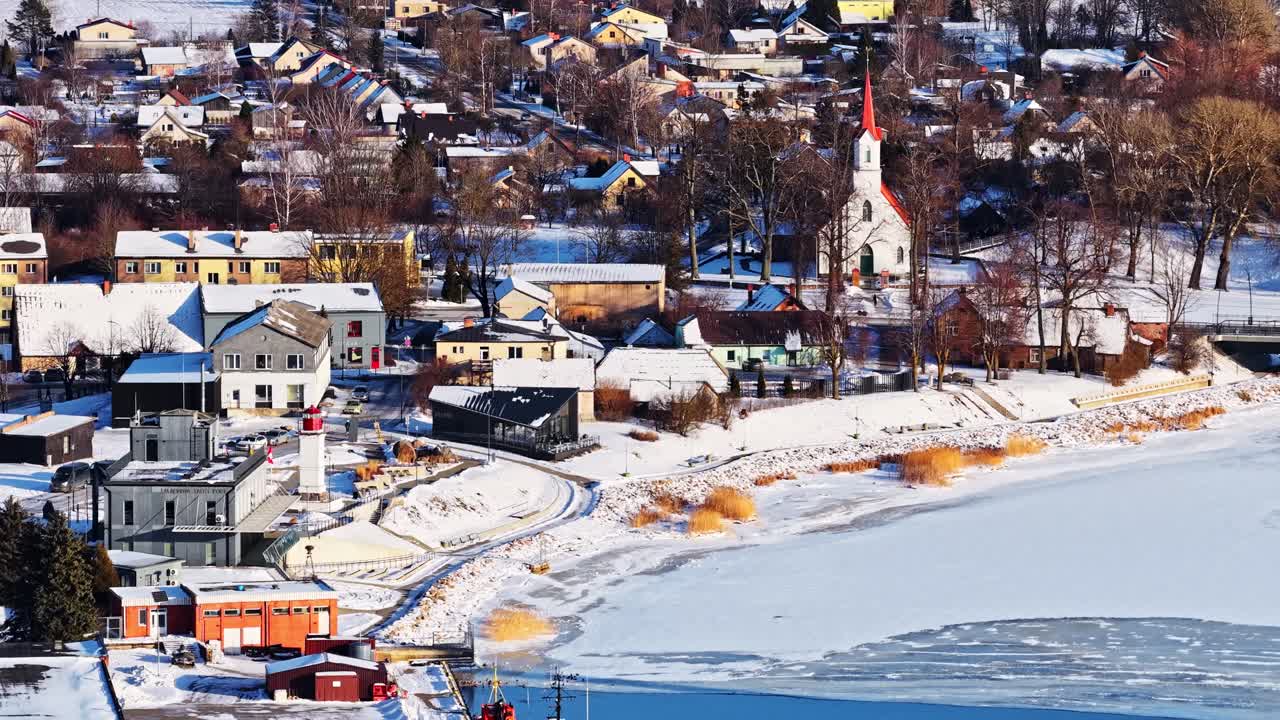 Salacgrīva, Latvia, lumipeitteinen kaupunki, joki ja satama talvella, ilmakuva.