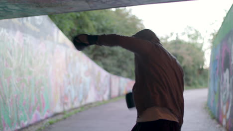 medium shot of young active man boxing in underpass, silhouetted by light