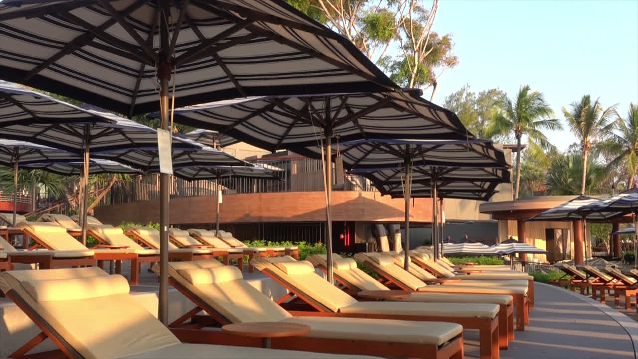 휴가 개념을 위한 호텔 리조트의 수영장 주변에 파라솔이 있는 침대 수영장