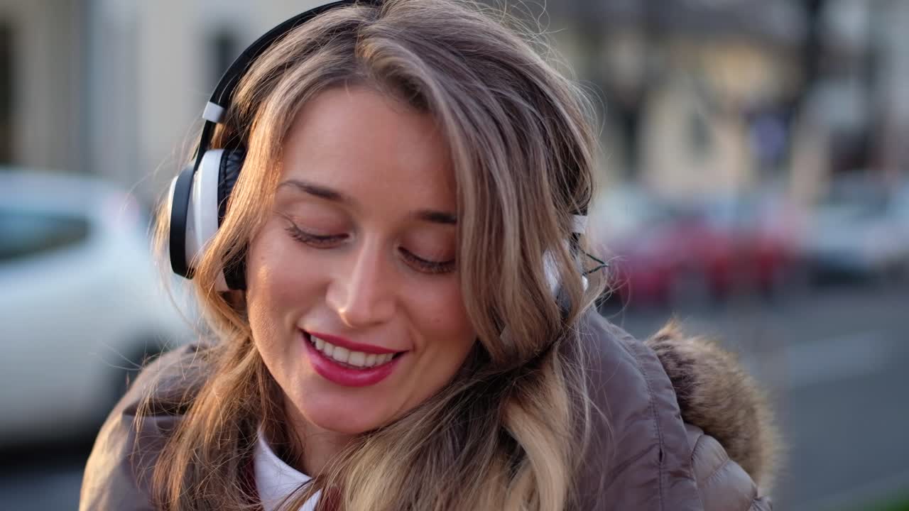 Woman listening to music in her headphones while singing along and dancing in the street